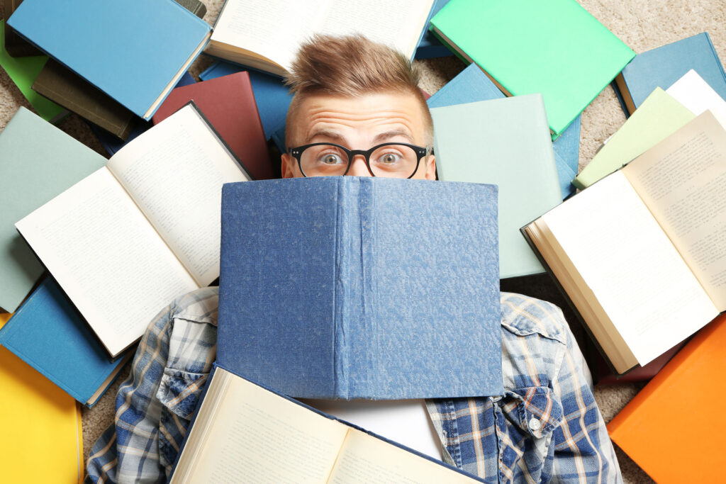 Man surrounded by open books looking surprised