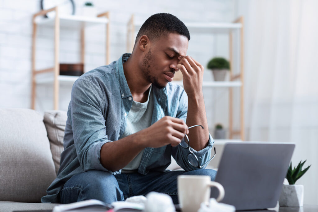 African American man experiencing fatigue while working from home.