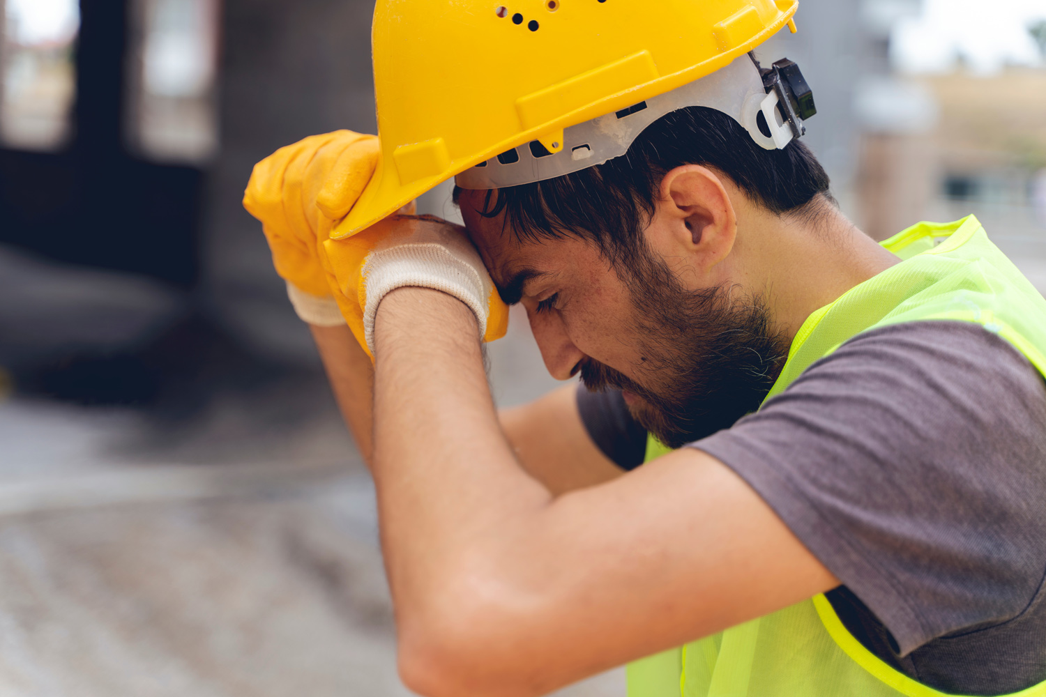 Tired male construction worker wiping his brow